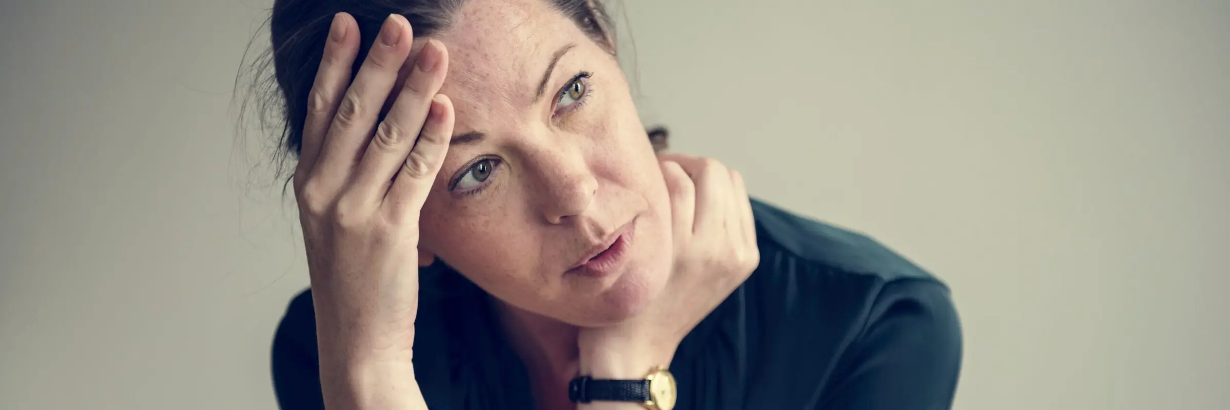 Erschöpfte Frau stützt den Kopf in beide Hände – TCM-Behandlung bei Burnout
