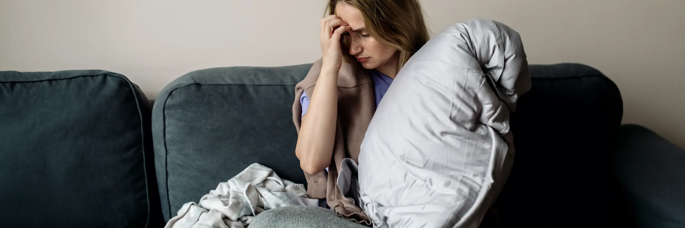 Frau liegt nachts wach im Bett und umklammert ihr Kissen – Akupunktur bei Schlafstörungen