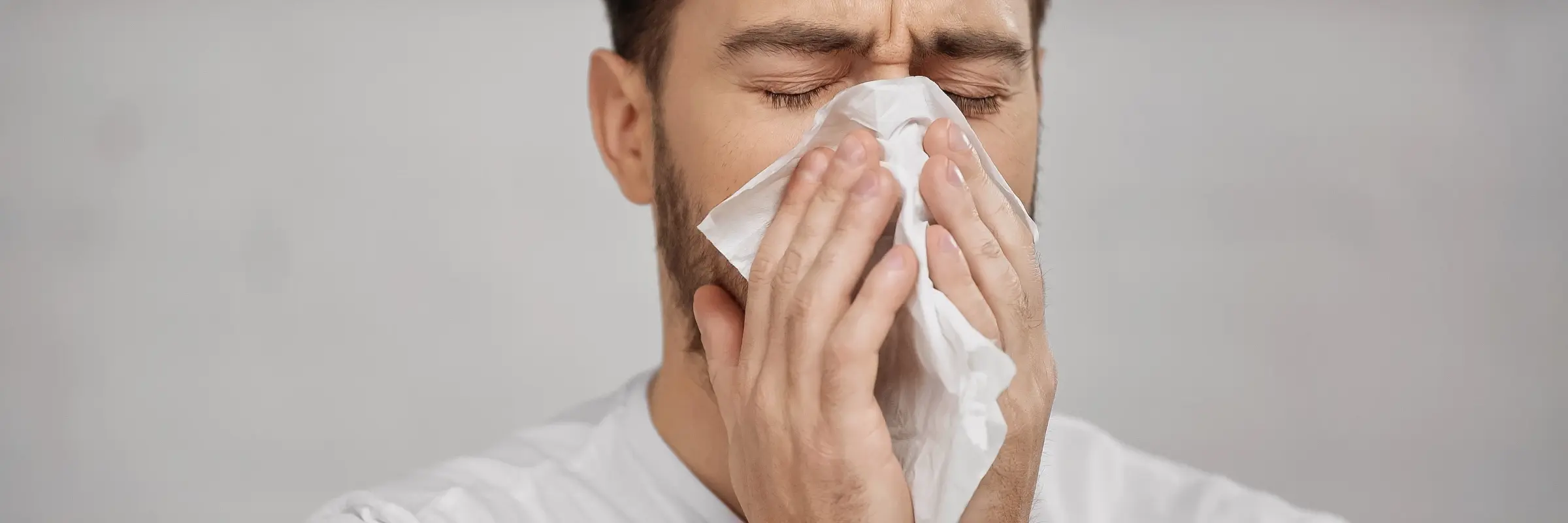 Frau putzt sich mit einem Taschentuch die Nase – TCM bei Allergien und Heuschnupfen